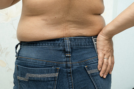 超重的亚洲女性在办公室表现出肥胖的腹部。