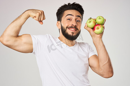 快乐的男人手里拿着苹果，穿着白色 T 恤水果