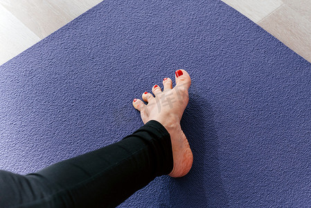伸展脚趾的瑜伽女人在运动垫上伸展脚趾