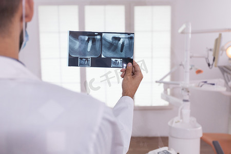 放射状图形摄影照片_牙医男医生分析在口腔医院工作的正畸牙齿医学放射线照相术