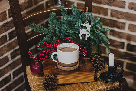 热巧克力杯摄影照片_圣诞热巧克力，在一个旧陶瓷杯里放着迷你棉花糖，在木制背景上放着蜡烛
