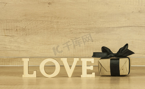 母亲节创意字摄影照片_字爱从木制字母与木背景上的礼品盒。