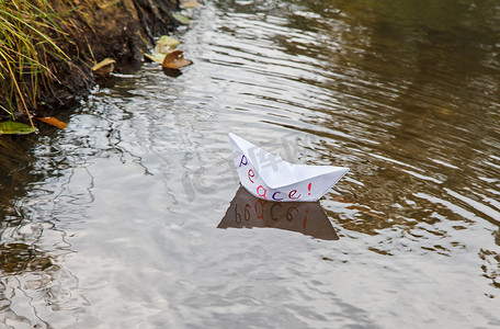 孤独的白色纸船，名为和平，漂浮在溪流上