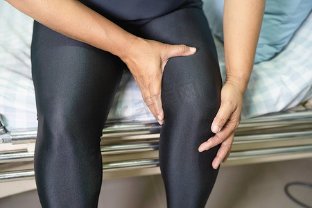 亚洲中年女性患者触摸膝盖疼痛，健康的医疗理念。