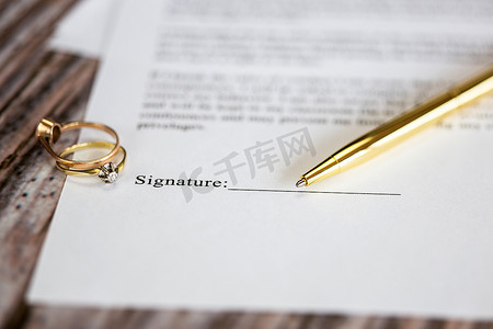 与两个金婚戒指和金笔的婚姻合同，婚前协议，宏观特写，签名，文件，协议概念