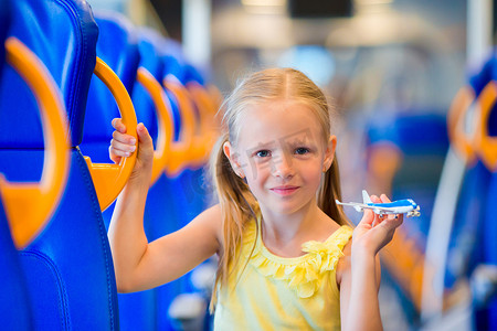 可爱的小女孩乘火车旅行，手里拿着飞机模型玩得很开心