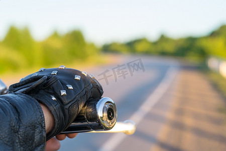 荆棘道路摄影照片_骑自行车的人的手在摩托车控制手柄上的特写和道路的景色