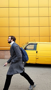 乌克兰，基辅 — 2020 年 2 月 25 日：一位成熟的男性商人急于在黄色背景下穿着灰色外套见面或工作。