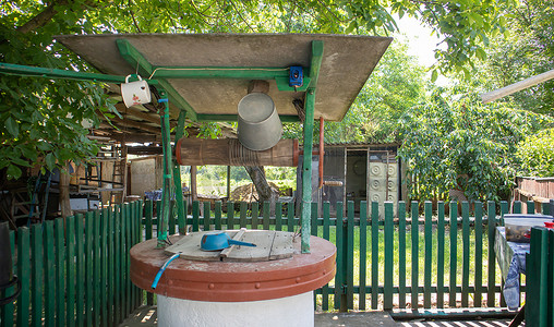 花园里有一口带桶的旧水井，一个用来从地上提水的金属把手。