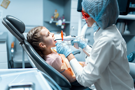 紫外线灯摄影照片_牙医用固化聚合紫外线灯为小病人提供牙齿修复和填充