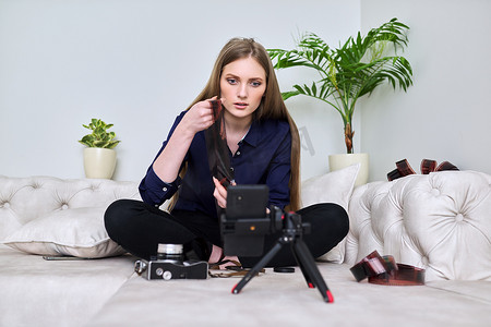 年轻女摄影师用老式相机在智能手机上录制视频