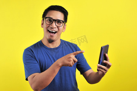 年轻帅气的亚洲男子用智能手机微笑，很高兴