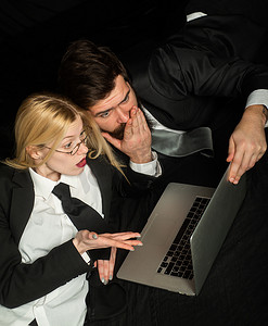两个商业伙伴一起使用笔记本电脑。美丽的年轻女商人和穿着正式西装的英俊商人正在使用笔记本电脑。