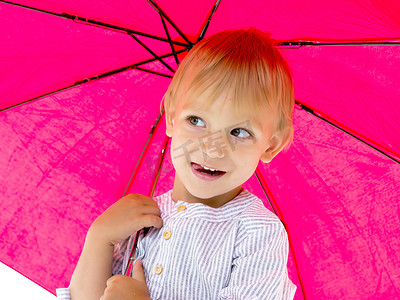 一个可爱的小男孩躲在伞下。