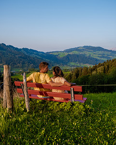 瑞士乡村，Ebnat Kappel，瑞士圣加仑，一对男人和一个女人在瑞士草地上的小屋外看日落