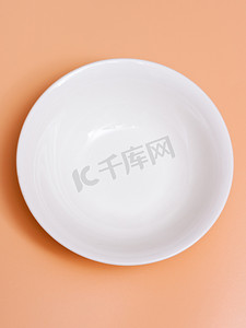陶瓷器皿摄影照片_在橙色背景的大陶瓷白色空的碗。