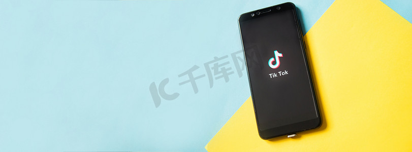 手机屏幕图标摄影照片_俄罗斯特维尔 — 2020 年 2 月 28 日，蓝色和黄色背景的智能手机屏幕上的 Tik tok 标志。