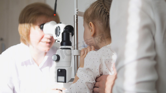 试试看摄影照片_小女孩和她的眼科妈妈-验光师检查小孩的视力