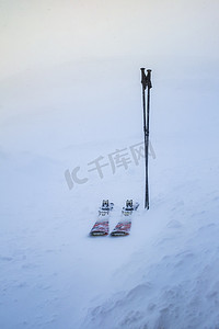 装订图标摄影照片_冬季暴风雪期间，一对滑雪板和棍子被困在雪中