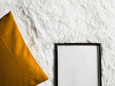 带有空白复制空间的黑色薄木框作为海报照片打印模型、金色垫枕和蓬松的白色毯子、平躺背景和艺术产品