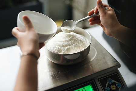 数字蛋糕数字摄影照片_面包店厨师在数字秤上称面粉