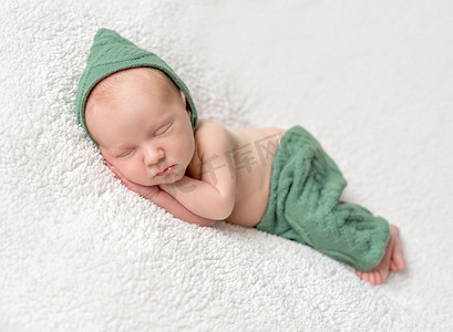 可爱的新生儿睡在绿色精灵帽子和内裤