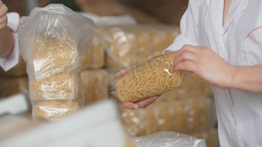 意大利面食工厂的工人正在包装生产线上的生通心粉