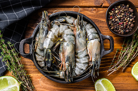 黑色虾摄影照片_新鲜的老虎虾、香料和香草放在平底锅里。
