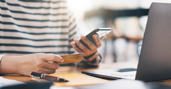 在线支付，女性手持信用卡，在家办公室使用智能手机进行在线购物