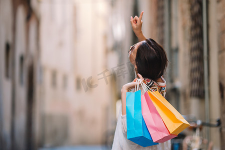 在欧洲狭窄的街道上提着购物袋的年轻女孩。