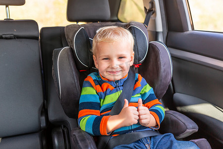 坐在汽车座椅上的小男孩在车里系好安全带。