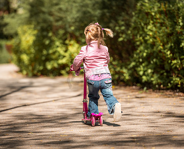 两岁的小女孩骑着她的踏板车