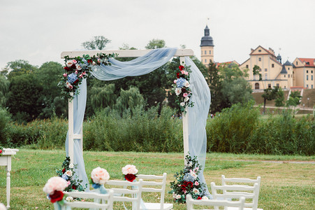 在绿色草坪上的街道上举行的婚礼。婚礼用鲜花拱门装饰