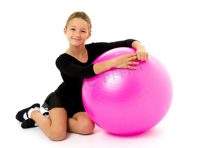 的小女孩在健身的大球上锻炼。