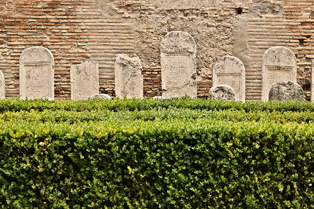 有黄杨木树篱和罗马白色大理石墓碑的花园。