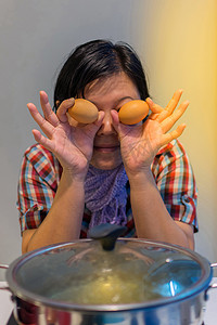 亚洲妇女将肉蛋放入火锅中做饭