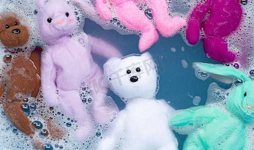 将带有玩具泰迪熊的兔子娃娃浸泡在洗衣粉水中