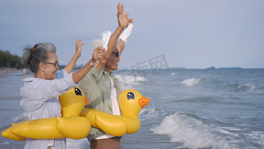 老年夫妇戴橡皮圈摘下医用口罩跑到海边享受生活