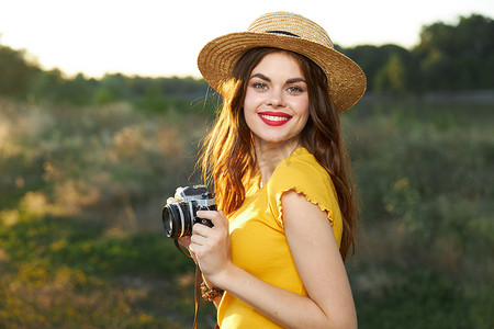 手拿相机的女摄影师微笑着红唇黄色T恤帽行走