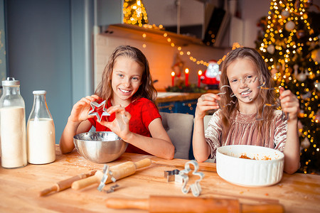 圣诞屋圣诞摄影照片_小女孩在装饰精美的客厅的壁炉旁制作圣诞姜饼屋。