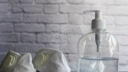在白色砖墙的背景下，灰色桌子上的白色防腐瓶和一种防护药物的面具。