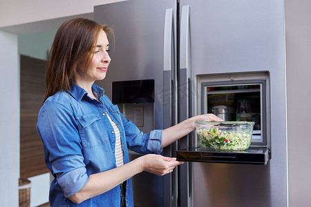 从冰箱里拿出一碗蔬菜沙拉的女人。
