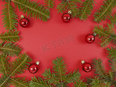 圣诞框架与冷杉树枝和红色背景上的小玩意。