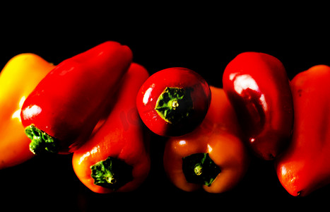黑色背景中的红黄辣椒，健康美味的素食产品