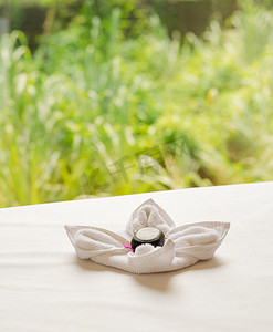 马萨上的折叠按摩毛巾、花瓣和鹅卵石
