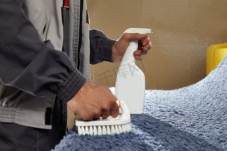 脏的污渍摄影照片_男子在地毯清洁服务中使用喷雾去除地毯上的污渍