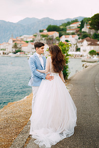 新娘和新郎在科托尔湾舒适的佩拉斯特老城附近的海边温柔地拥抱