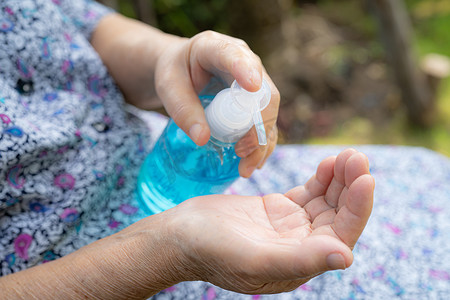 亚洲老年或老年老妇患者用蓝色酒精消毒凝胶洗手，以保护安全感染并杀死Covid-19冠状病毒、细菌和病菌。