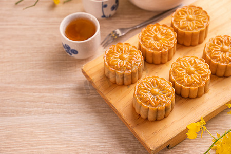 月饼秋天摄影照片_月饼、月饼、亮木桌茶具和带复制空间的盘子的中秋节假期概念设计，特写。