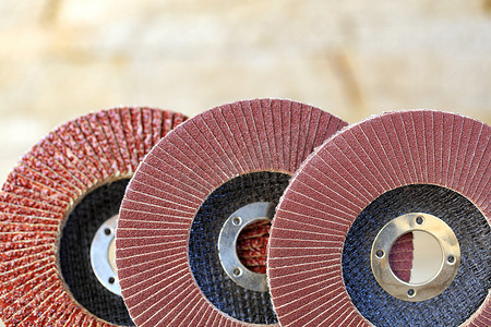米色磨砂背景摄影照片_浅米色背景上的木材和金属上的不同颗粒的翻板磨轮不清晰。